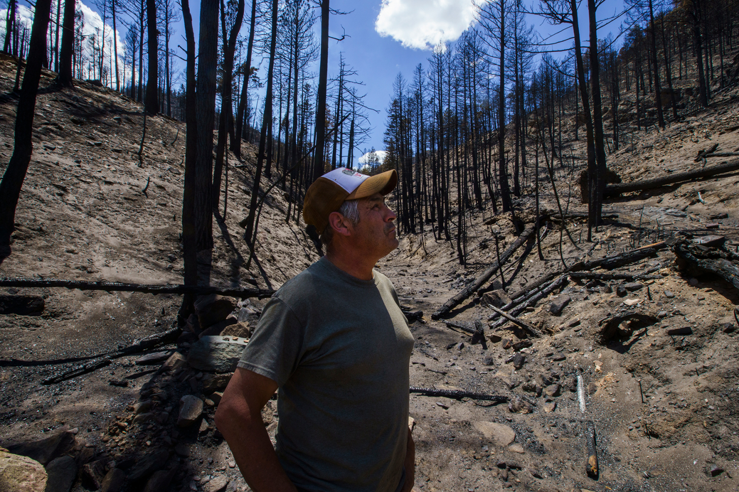 Patrick Griego stands in what was a creek bed in the burn area on his property. Nadav Soroker/Searchlight New Mexico