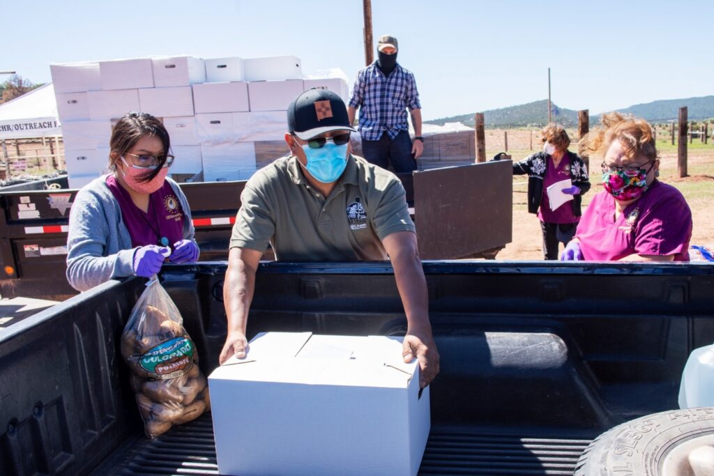 Sam Bryant of the Southwest Indian Foundation in Gallup loads a box of groceries into a pickup on the Navajo Reservation at Oak Springs, Arizona.