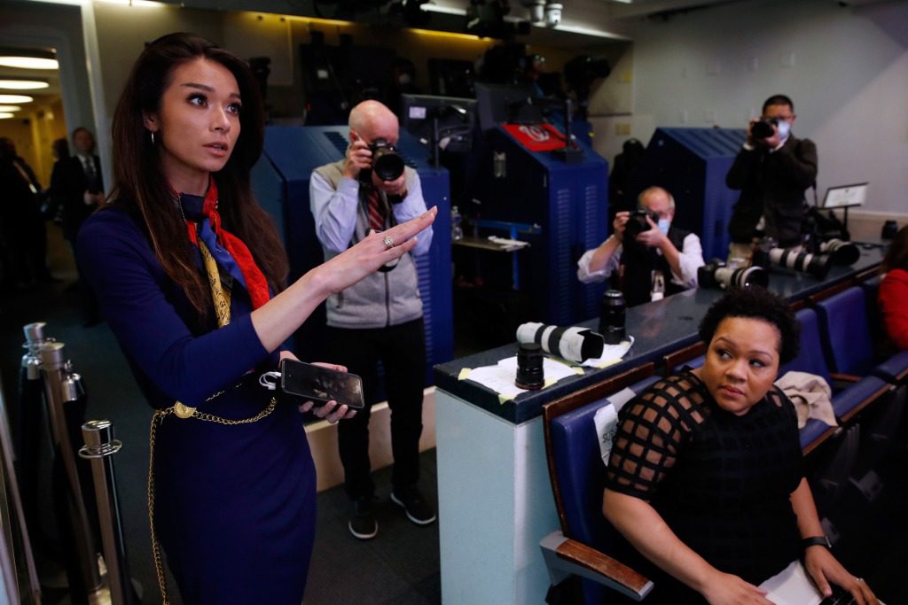 PBS reporter Yamiche Alcindor, seated, watches as One America News (OAN) White House Correspondent Chanel Rion asks a question of President Donald Trump during a briefing about the coronavirus in the James Brady Press Briefing Room of the White House, Monday, April 20, 2020, in Washington. (AP Photo/Alex Brandon)