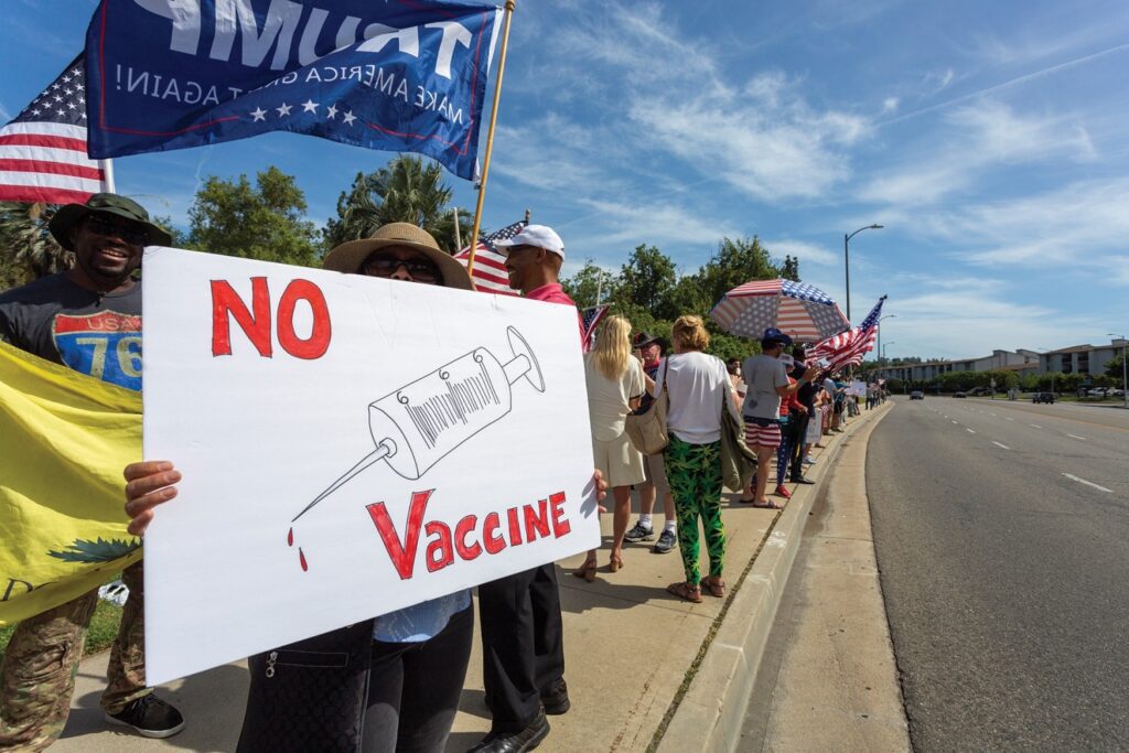 WOODLAND HILLS, CA - MAY 16: A protester holds an anti-vaccination sign as supporters of President Donald Trump rally to reopen California as the coronavirus pandemic continues to worsen, on May 16, 2020 in Woodland Hills, California. The protesters, organized by the activist group, Latinos 4 Trump 2020, are angry about restrictions related to the virus that causes COVID-19 disease and are calling for such restrictions regarding businesses, social distancing and recreational movement to end as soon as possible. (Photo by David McNew/Getty Images)
