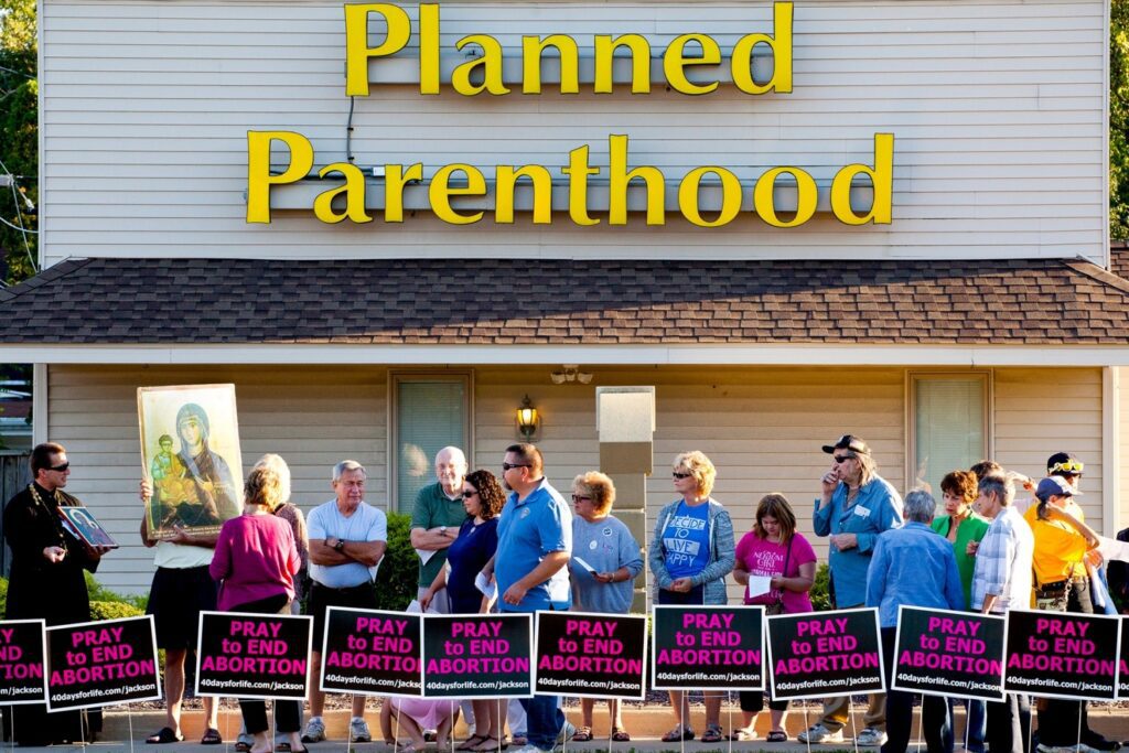 People protest outside of Planned Parenthood on Wednesday, Sept. 23, 2015, in Jackson, Mich. Participants sang and prayed to end abortion and close Planned Parenthood. 