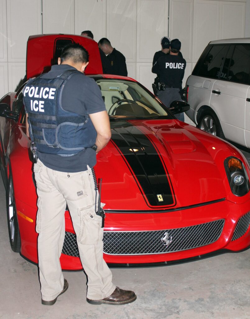 In this Oct. 17, 2011 photo provided by U.S. Immigration and Customs Enforcement (ICE), agents inspect a Ferrari at the Malibu, Calif., mansion of the son of Equitorial Guinea's president, Teodoro Nguema Obiang Mangue, during the execution of a search warrant. Mangue must sell the $30 million Malibu mansion, the Ferrari and Michael Jackson memorabilia and then give the proceeds to the citizens of his impoverished country, under a settlement announced Friday, Oct. 10, 2014 by U.S. authorities who said he bought the lavish items with money stolen from the African nation. Mangue, who is also Equatorial Guinea's second vice president, agreed to turn over $20 million from the sale of these assets to a charitable organization to be used to benefit the people of his country, the U.S. Department of Justice said. Another $10.3 million will be forfeited to the U.S. government. (AP Photo/U.S. Immigration and Customs Enforcement)